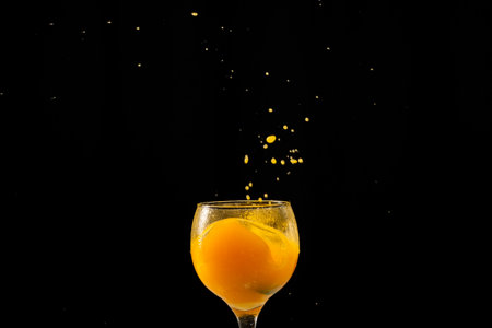 Splash in a glass goblet with orange juice inside. Isolated on black background.の写真素材