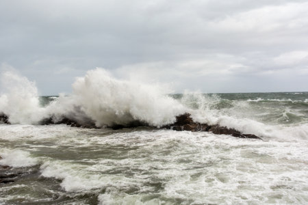 Immense sea rock covered by a large wave. Force of nature. Winterの写真素材
