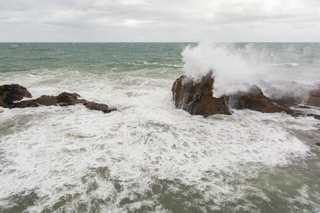 Waves hitting a sea rock with great force. winter storm.の写真素材