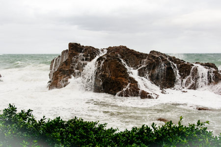 Immense sea rock covered by a large wave. Force of nature. Winterの写真素材