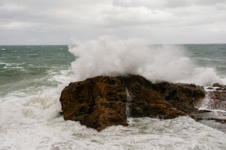 Immense sea rock covered by a large wave. Force of nature. Winterの写真素材