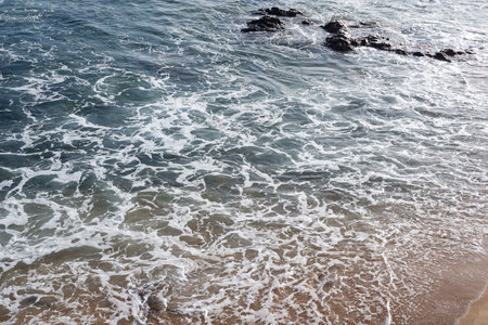 Seaside of a beach with small foaming waves. Sunny day, calm sea water.の写真素材