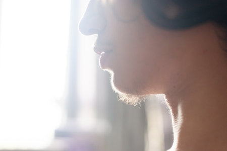 Close-up portrait of the side of a young adult's face against light from the window. portrait at home.の写真素材