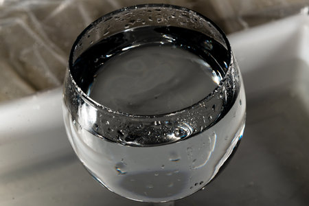 A glass wine glass with water inside. Isolated on dark background.の写真素材