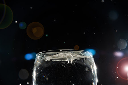 Transparent glass bowl filled with water with splashes of water around it. Splash Effect. Isolated on dark background.の写真素材