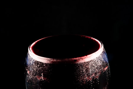 Close-up of the top of a clear glass goblet filled with wine. Isolated on dark background.の写真素材