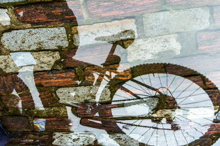 Reflection of person and bicycle in a puddle of rainwater in the river. Abstract blur.の写真素材