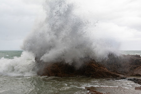 Immense waves hitting a large rock at the edge of the beach. Force of nature. Winterの写真素材