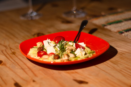 A red plate with salads inside on a wooden table. Wine accompaniment. food photographyの写真素材