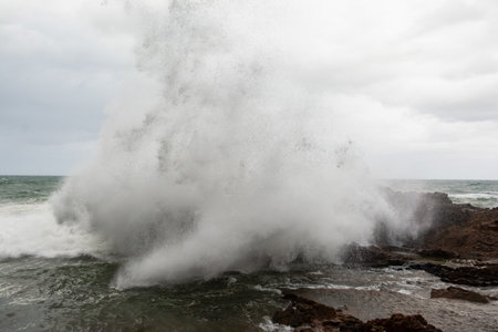 Immense waves hitting a large rock at the edge of the beach. Force of nature. Winterの写真素材