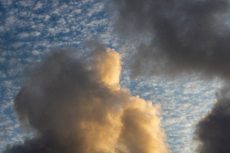 Beautiful yellow clouds in the late afternoon against a cloudy blue sky. Vibrant and dramatic nature.の写真素材