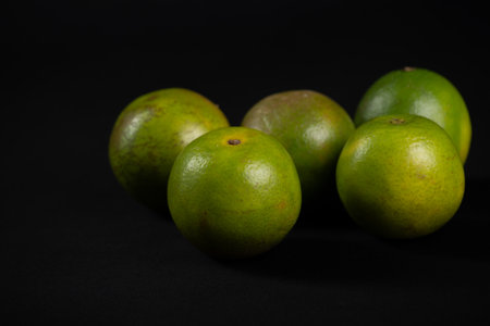 Group of still green oranges on a black background. Healthy eating concept.の写真素材