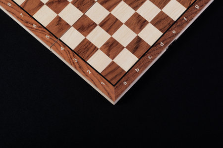 Part of an empty wooden checkers or chess board on a black background.の写真素材