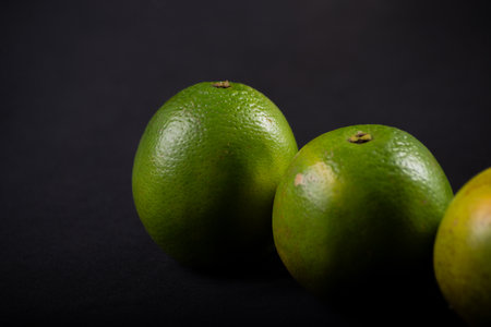 Close-up of three green oranges on a black background. Healthy eating concept.の写真素材