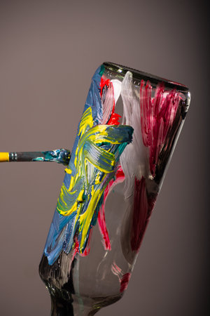 Close-up portrait of a glass bottle being painted with a brush. Isolated on brown background.の写真素材
