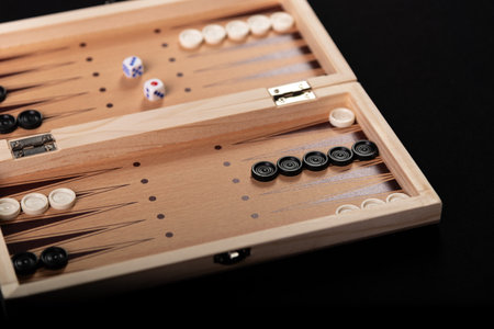 Board for playing backgammon with pieces and dice on a black background. Board game, pastime, fun.の写真素材