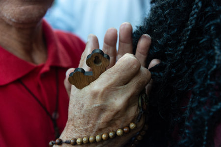 Salvador, Bahia, Brazil - July 27, 2024: Portrait of hands of a Catholic believer holding a rosary during mass. Pelourinho, historic center of the city of Salvador, Bahia.のeditorial素材