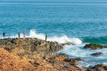 Salvador, Bahia, Brazil - July 06, 2019: Fishermen are seen on top of the rocks at Paciencia beach fishing with rods in the city of Salvador, Bahia.のeditorial素材