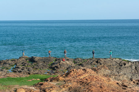 Salvador, Bahia, Brazil - July 06, 2019: Fishermen are seen on top of rocks fishing with rods on Paciencia beach, in the city of Salvador, Bahia.のeditorial素材