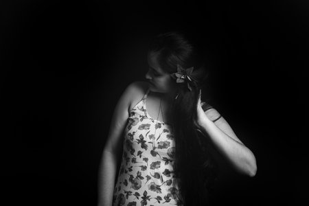Black and white portrait of a woman running her hand through her long, straight hair. Studio shot.の写真素材