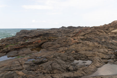 View of dark sea rocks against the ocean and cloudy sky. Preserved nature. Salvador, Brazilの写真素材