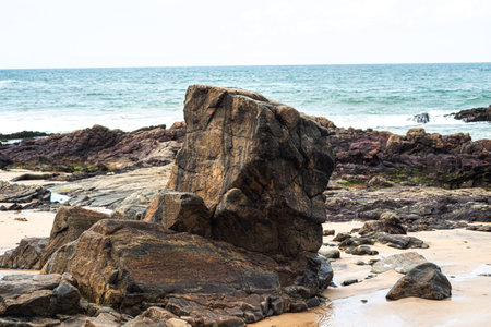 View of dark sea rocks against the ocean and cloudy sky. Preserved nature. Salvador, Brazilの写真素材