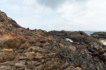 View of dark sea rocks against the ocean and cloudy sky. Preserved nature. Salvador, Brazilの写真素材