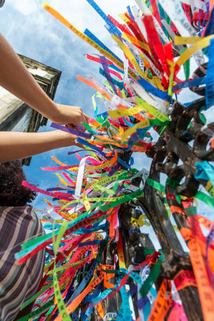 Salvador, Bahia, Brazil - December 27, 2019: Catholics are seen tying colorful ribbons as souvenirs at the gate of the Senhor do Bonfim church in Salvador, Bahia.のeditorial素材