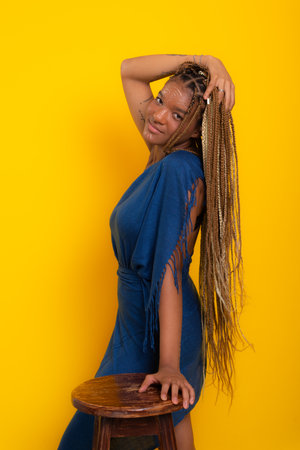 Photo of beautiful young brunette woman with braids in her hair wearing blue clothes, standing,...