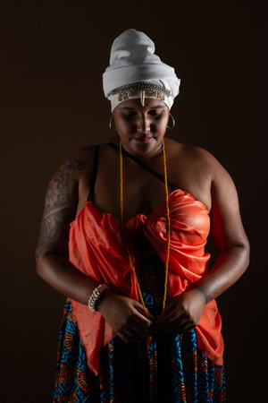 Salvador, Bahia, Brazil - October 21, 2024: Beautiful black woman wearing traditional Candomble clothes, posing for photo. Isolated on brown background. Salvador, Bahia.の写真素材