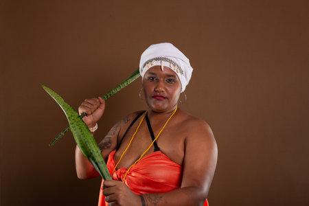 Salvador, Bahia, Brazil - October 21, 2024: Woman in traditional CandomblÃ© clothing, holding the sword of Saint George plant, posing for a photo.の写真素材