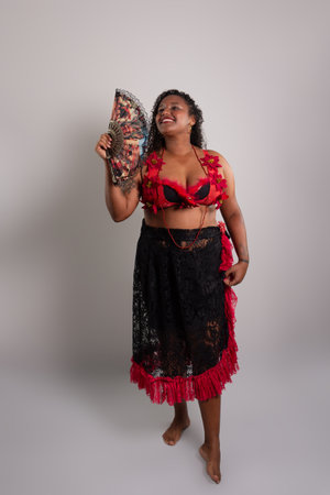 Salvador, Bahia, Brazil - October 21, 2024: Beautiful black woman standing wearing traditional clothing with fan in hand. Isolated on white background. Salvador, Bahia.の写真素材