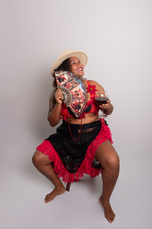 Salvador, Bahia, Brazil - October 21, 2024: Woman wearing a hat and clothing holding a glass of wine and a fan. Isolated on white background. Salvador, Bahia.の写真素材