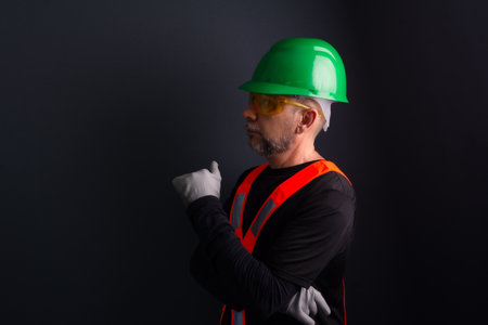 Photo of a worker wearing a green helmet, reflective vest and protective glasses. isolated on gray background.の写真素材