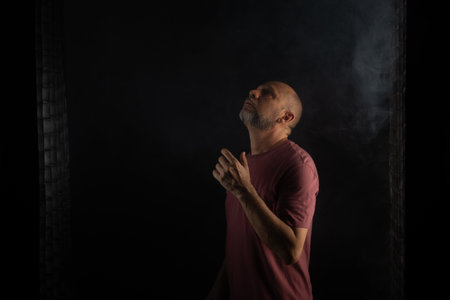 Bald and bearded man looking up. Isolated on smoky black background.の写真素材