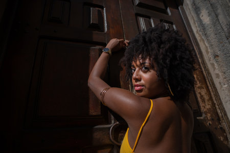 Portrait of beautiful woman wearing yellow dress standing by old brown wooden door. Happy person traveling concept.の写真素材