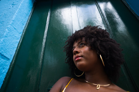 Close-up portrait of woman with afro hair against green door. Happy person on a trip.の写真素材