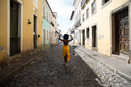 Portrait of beautiful woman wearing yellow dress standing on old cobblestone street. Happy person on travel.の写真素材
