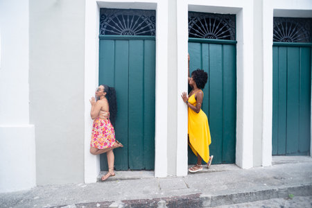 Two young women leaning against wooden door of old house. Friendship concept. People traveling.の写真素材