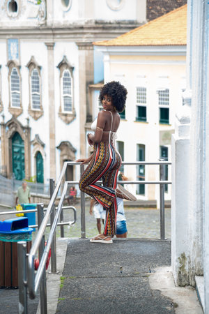 Young black woman with afro hairstyle looking at the camera against a church and old houses in the background. Happy and confident person. Brazilの写真素材