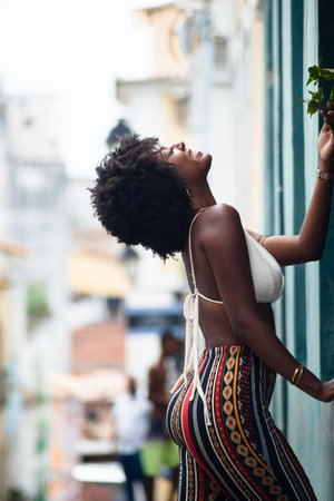 Beautiful, very smiling and happy woman leaning against a wall of an old house. Brazilの写真素材