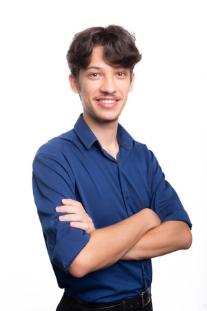 Young handsome student in blue shirt with crossed arms looking at camera. Isolated on white background. Confident person. Professional concept.の写真素材