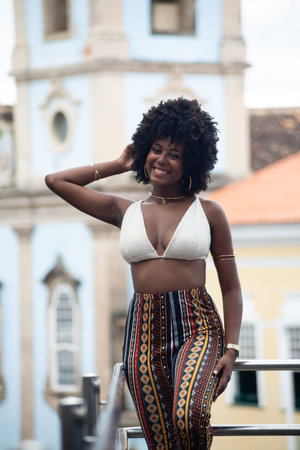 Young black woman with afro hairstyle looking at the camera against a church and old houses in the background. Happy and confident person. Brazilの写真素材