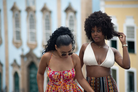 Two young friends standing together against old houses in the background. Empowered people on a...