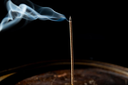 Blue-white smoke coming from the tip of an incense stick. Studio shot.の写真素材