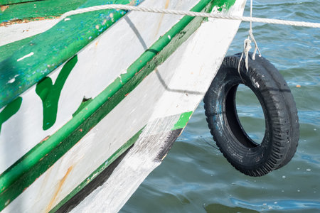 Detail of the tip of a wooden boat with a black tire tied to the nose. Maritime transport. Brazilの写真素材