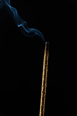 Close-up of smoking incense sticks against a dark background. Studio shot.の写真素材