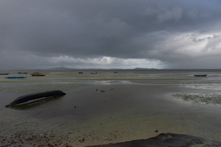 A wooden fishing canoe turned upside down on a beach at low tide. Rainy day.の写真素材