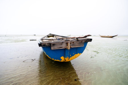 Fishing boat anchored on the sand of a dry beach. Quite rainy day with dense clouds. Means of...