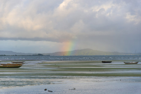 Boats on a beach. Low tide. Cloudy day with rainbow. Means of transport.の写真素材